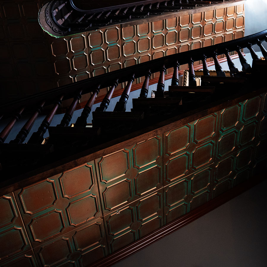 The original grand winding staircase with carved wooden balusters and copper-tin wall panels