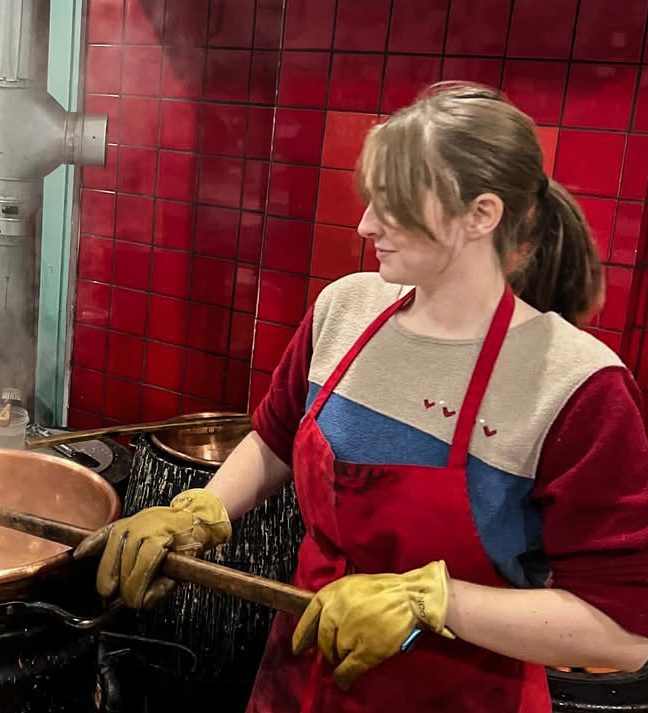 A candy maker stirring candy in a copper kettle